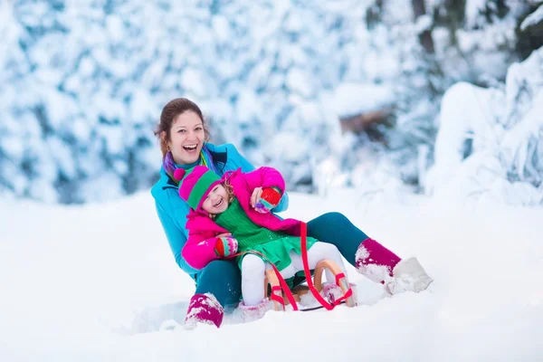 Mutter und Kind rodeln in einem verschneiten Park — Stockfoto