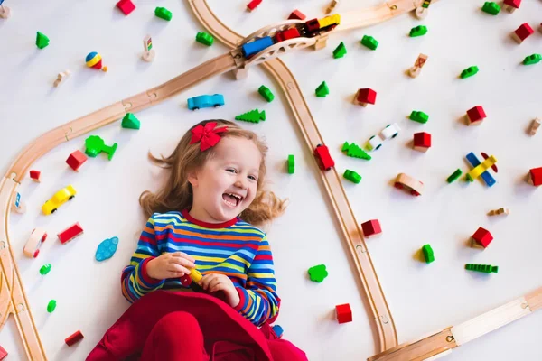 Little girl playing with wooden trains — Stock Photo, Image