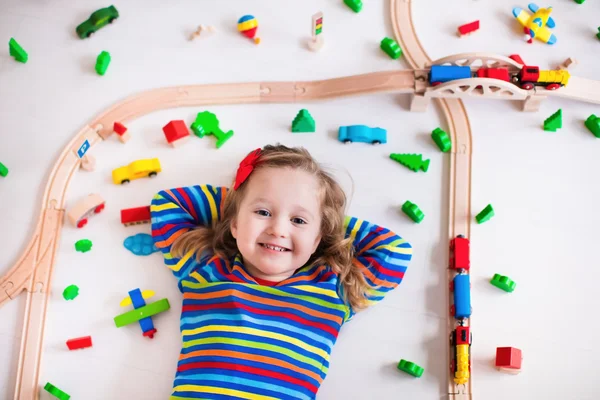 Kleines Mädchen spielt mit hölzernen Zügen — Stockfoto