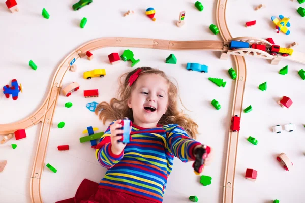 Menina brincando com trens de madeira — Fotografia de Stock