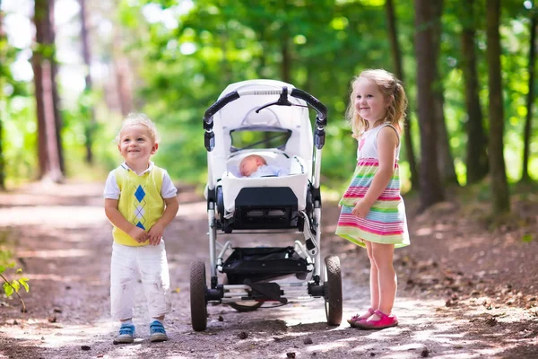 Children pushing stroller with newborn baby — Stock Photo, Image