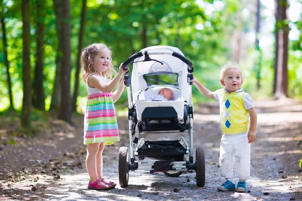 子供が生まれたばかりの赤ちゃんのベビーカーを押す — ストック写真