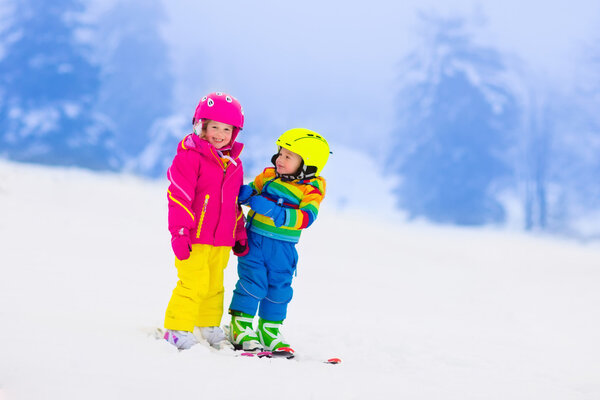 Two children skiing in snowy mountains