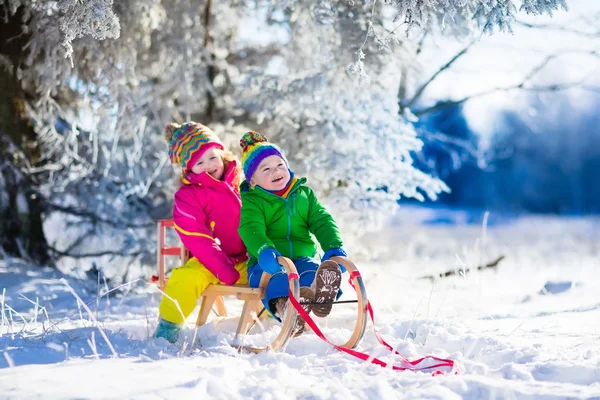 Niños montando un trineo en un parque de invierno nevado — Foto de Stock