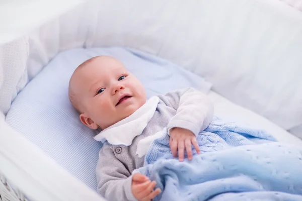 Niño en una cuna debajo de una manta de punto — Foto de Stock