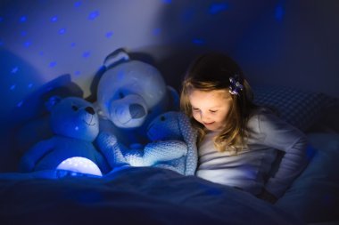 Little girl reading a book in bed clipart