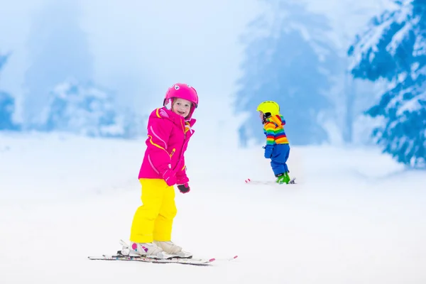 Двое детей катаются на лыжах в снежных горах — стоковое фото