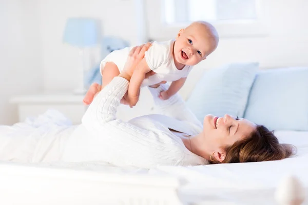 Matka i dziecko na białym łóżku — Zdjęcie stockowe