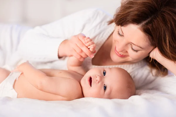 Mother and baby on a white bed Royalty Free Stock Images