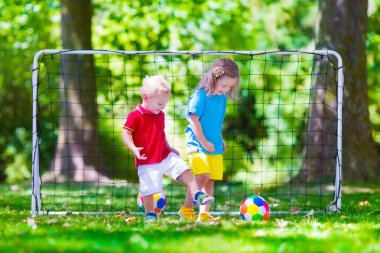 Çocuklar açık havada futbol oynarken