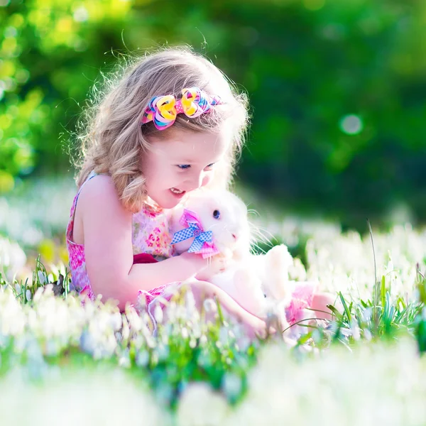 Kleines Mädchen spielt mit einem Kaninchen — Stockfoto