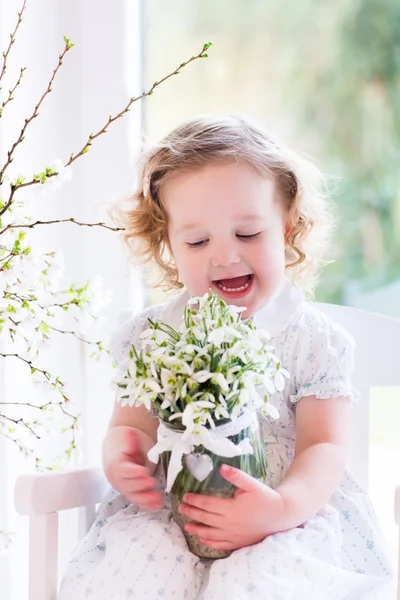 Девочка с первыми весенними цветами дома — стоковое фото
