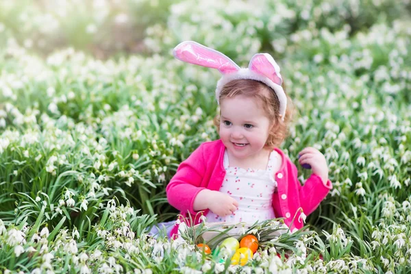 Маленькая девочка с кроличьими ушами на пасхальных яйцах — стоковое фото