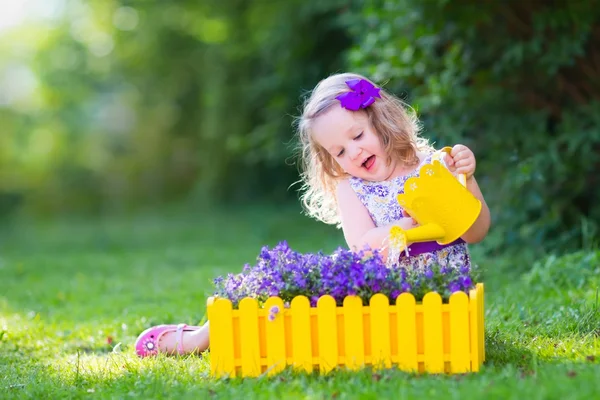 Little girl watering farden flowers — Stock Photo, Image