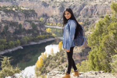 Gezgin kadın, sırt çantasıyla bir uçurumun önünde nehri olan.