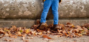 Sonbaharda parkta oynayan küçük bir çocuğun ayakları.