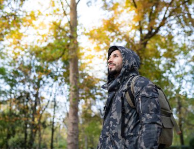Ormanda sırt çantası ve kapüşonlu bir adam, göçebe gezgin.