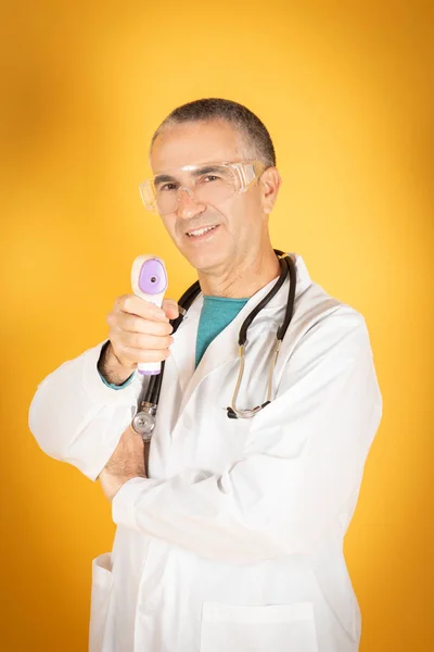 Doctor Senior Usando Termómetro Infrarrojo Para Comprobar Coronavirus Fondo Amarillo — Foto de Stock