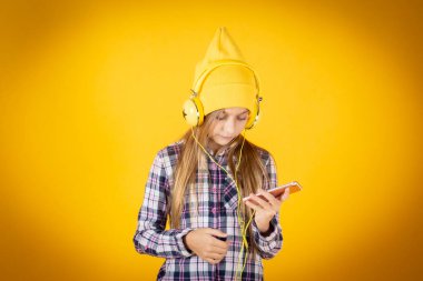 Akıllı telefonları ve kulaklıkları olan küçük bir kız.