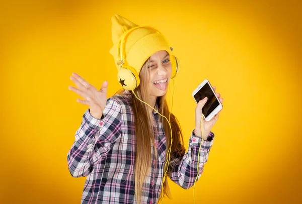 带着耳机和智能手机听黄色背景音乐的金发小女孩 — 图库照片