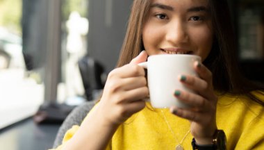 Kafede kahve içen Asyalı bir kız.