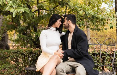 Parktaki bankta oturan birbirine aşık çift.