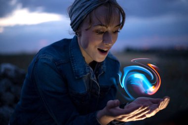 Elinde ilginç bir şey tutarken gülümseyen bir kadın.