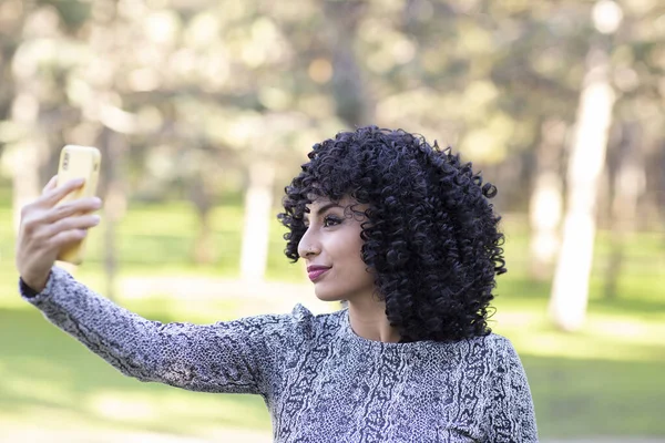 Latin woman with afro hair, with her mobile