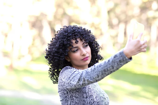 Latin woman with afro hair, with her mobile