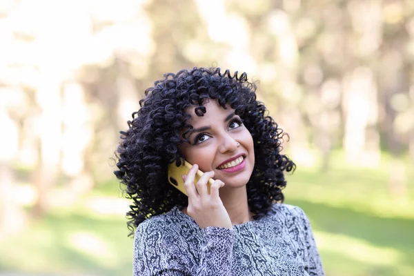 Latin woman with afro hair, with her mobile