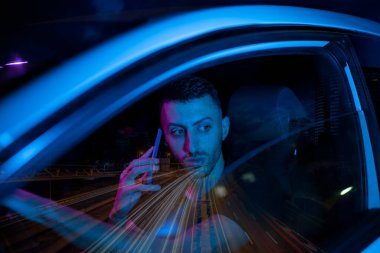 Geceleri araba kullanan ve konuşan bir adam.