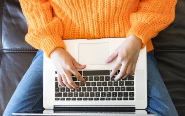 Evde dizüstü bilgisayar kullanan bir kadının elleri.