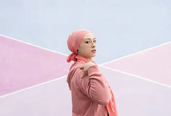 woman with cancer pink scarf warm background