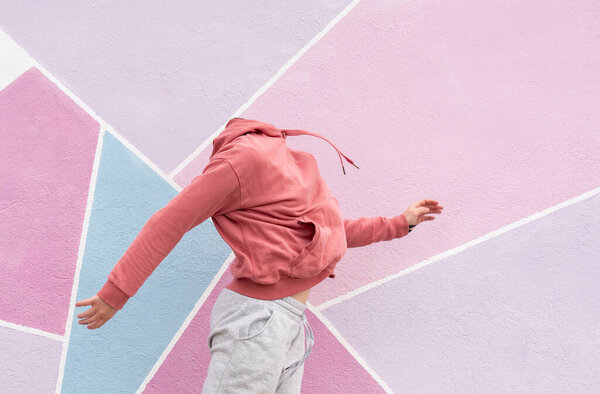 woman jumping on a pink background listening to music