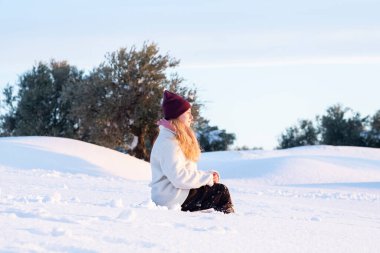 Sarışın kadın karda eğleniyor, güneşli bir gün.