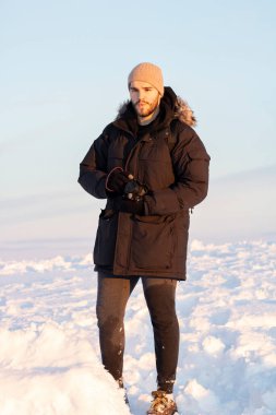 Kalın elbiseli bir adam ve karda kamera.