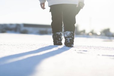 Kar ve güneş ışınları arasında yürüyen ayaklar