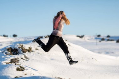Sarışın kız karda eğleniyor, güneşli bir gün.