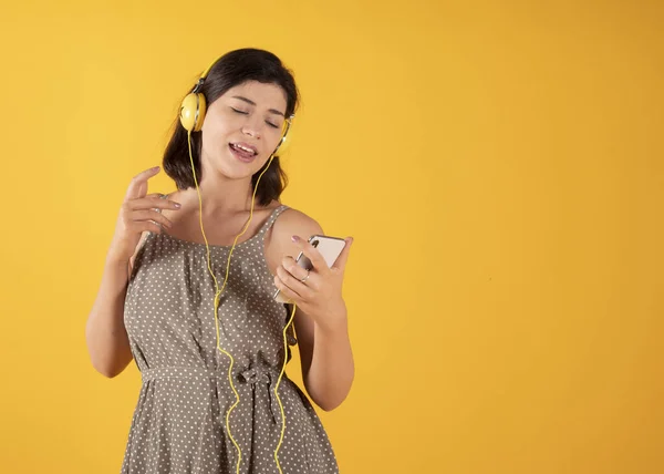 Mujer Con Auriculares Teléfono Celular Escuchando Música Cantando Fondo Amarillo —  Fotos de Stock