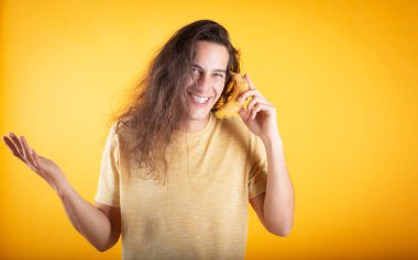 Mavi gözlü, uzun saçlı, muzlu, sarı renkli yakışıklı bir adam.