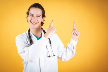 Steteskopu olan yakışıklı doktor, mutlu, gülümseyen fotokopi alanı sarısı arka planı.