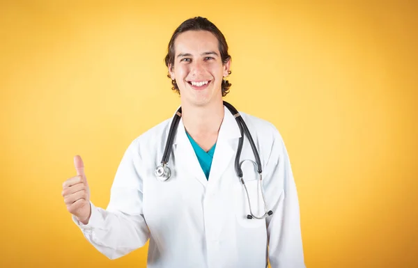 Joven Médico Masculino Sonriendo Con Dedo Sobre Fondo Amarillo Espacio —  Fotos de Stock