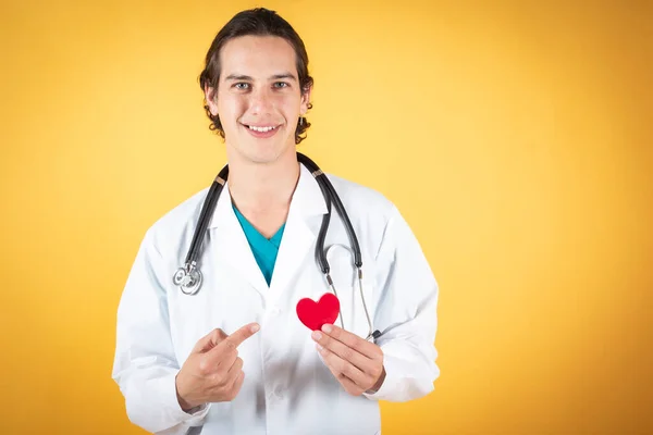 Молодий Чоловік Лікар Посміхається Концепцією Здоров Червоного Серця Жовтому Фоні — стокове фото