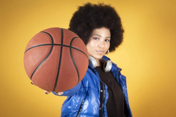 Günlük kıyafetleri ve basketbol topuyla Afrikalı Amerikalı kadın, retro, eğlenceli, sarı arka plan, kopyalama alanı