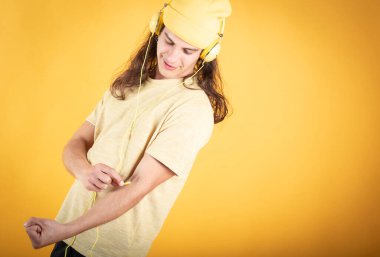 Sarı kulaklık takan, sarı kulaklık takan, sarı arka planda müzik dinleyen, mekanı kopyalayan mavi gözlü yakışıklı bir adam.