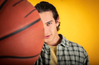 Yakışıklı, beyaz, mavi gözlü, sıradan elbiseli, basketbol sarısı arka planı olan, boşluğu kopyalayan bir adam.