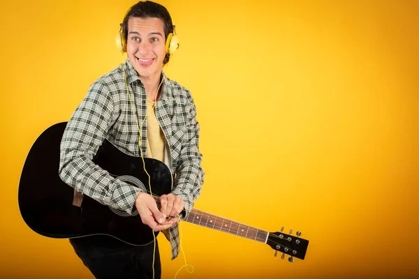 young man guitar teacher, singer-songwriter,playing the guitar,yellow background, copy space