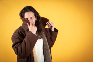 Yakışıklı adam yüzünü kışlık paltosuyla örtüyor.