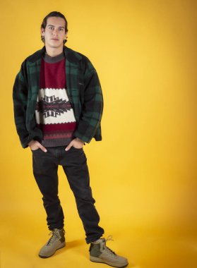 Kışın poz veren yakışıklı, uzun saçlı adam. Sarı arka plan, kopyalama alanı.