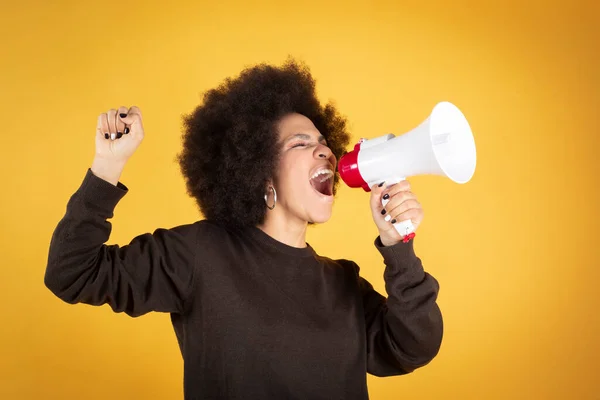 Karışık ırk kadını, politik sendikalist feminist, kendini eşitliğe adamış, megafona bağırıyor, sarı arka plan, kopyalama alanı